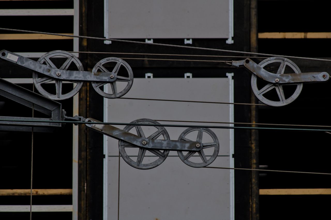 Detailed view of metallic pulleys on a modern building facade, capturing industrial design elements.
